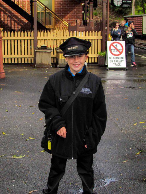 A little boy dressed as a train conductor.
