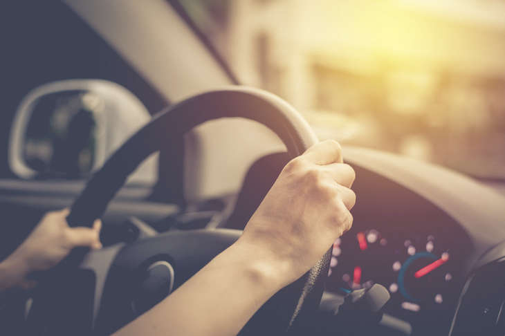 Hands on a steering wheel, driving a car. Small differences between Melbourne and Miami.