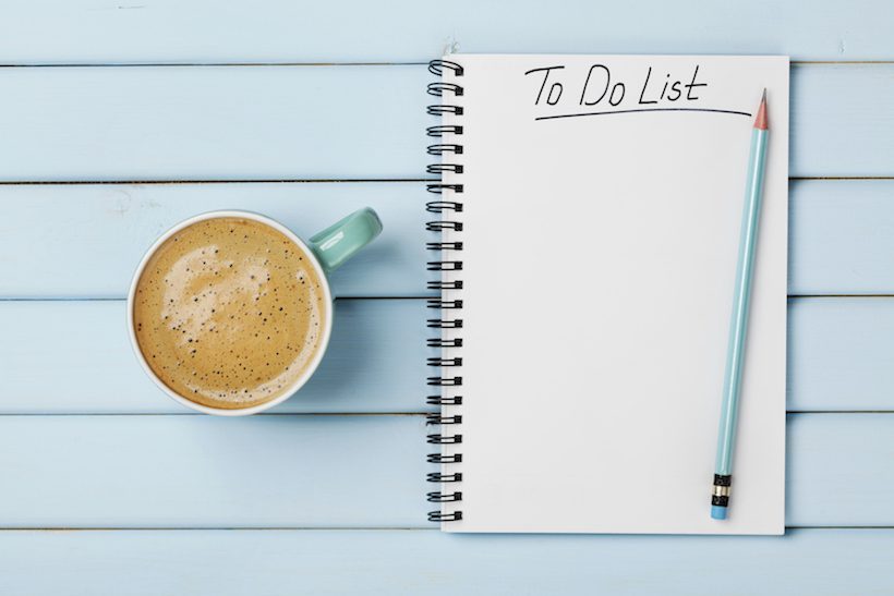 Coffee cup and notebook with to do list on blue rustic desk from above. Visa process.