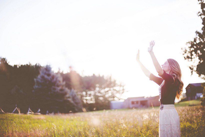 Woman outside with raised arms. Ground, center, shield, cleanse.