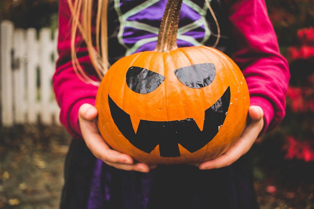 Child holding Halloween pumpkin.