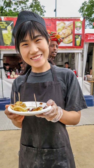 A young Asian woman offering food samples.