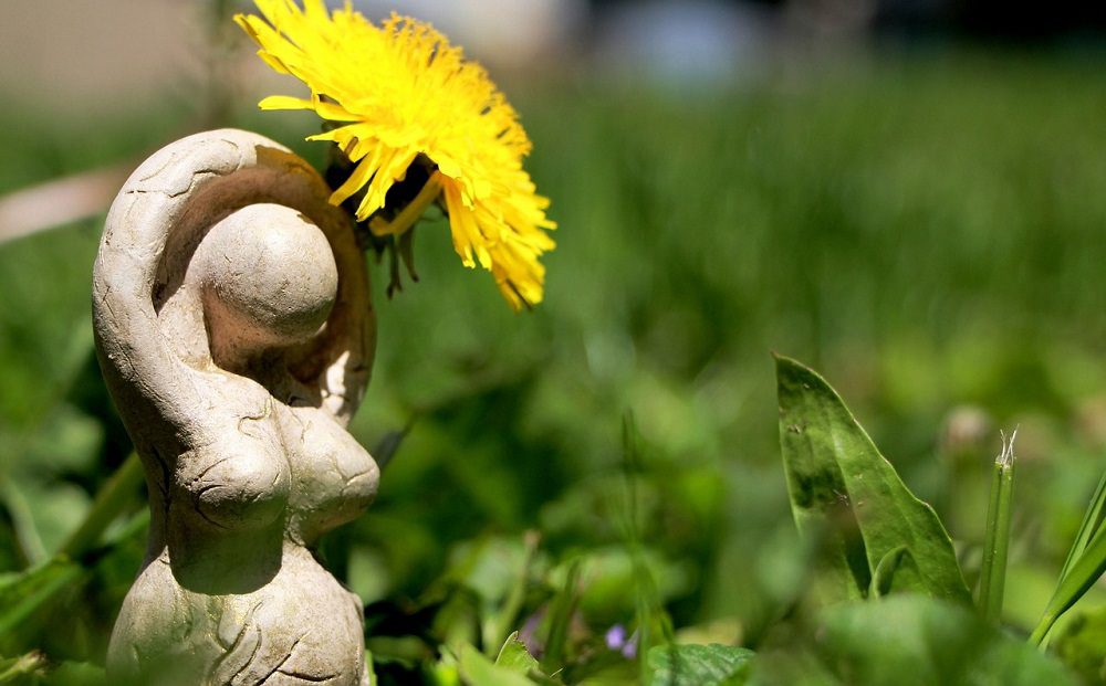 Spirituality, paganism. Little statue of a goddess with a flower.