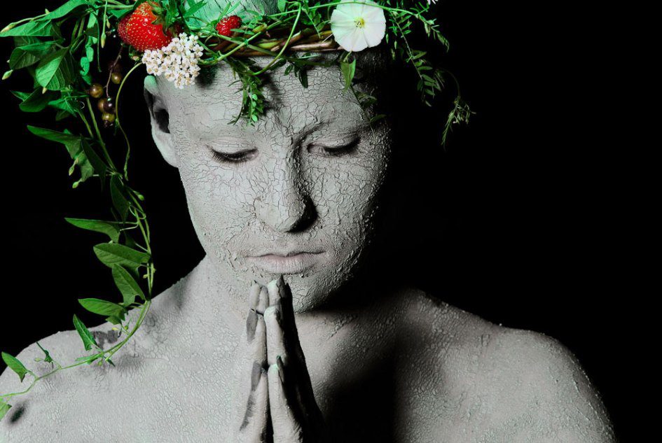 Environment - praying woman covered in mud and wearing flowers
