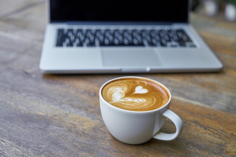 Coffee next to a laptop.