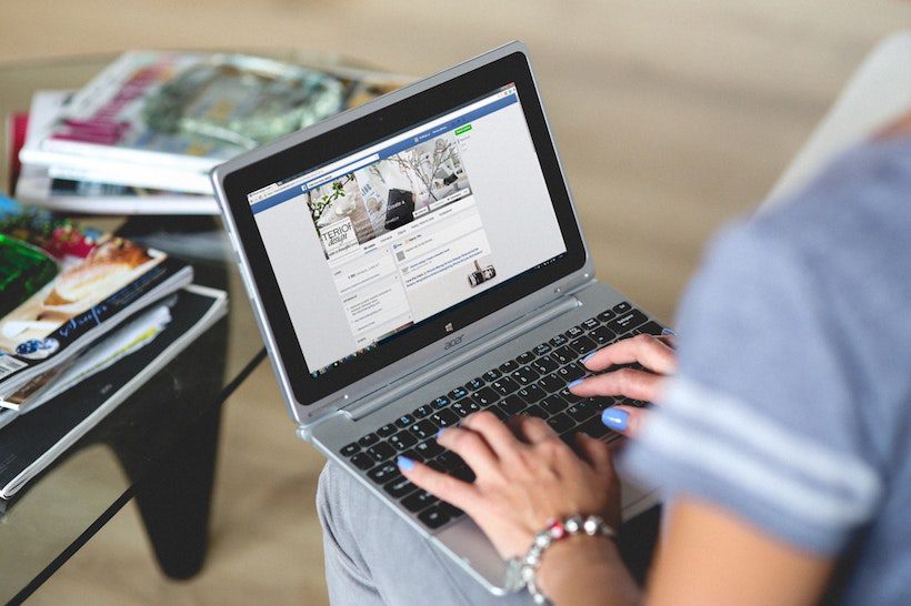 A woman's hands using a laptop, on Facebook.