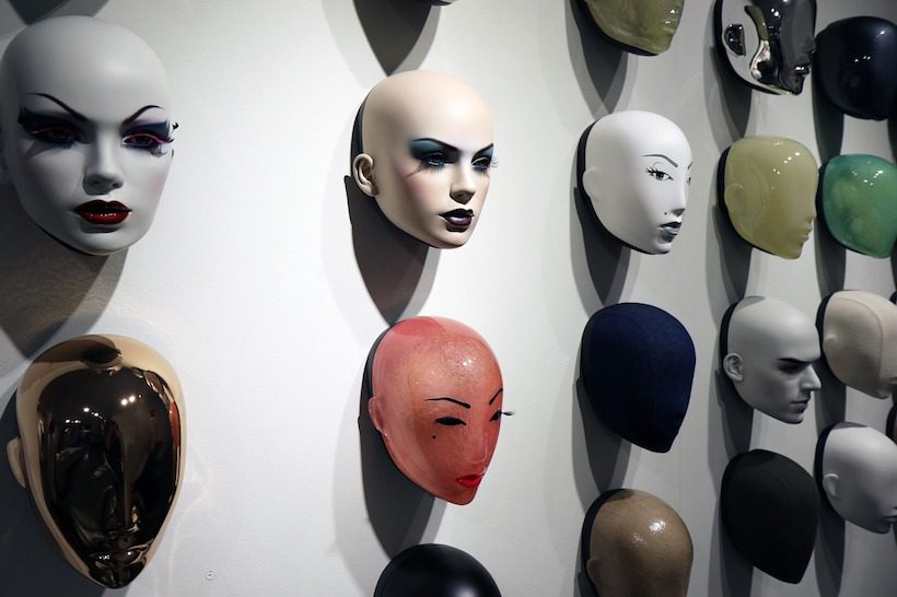 Art installation of human-like heads on a wall.