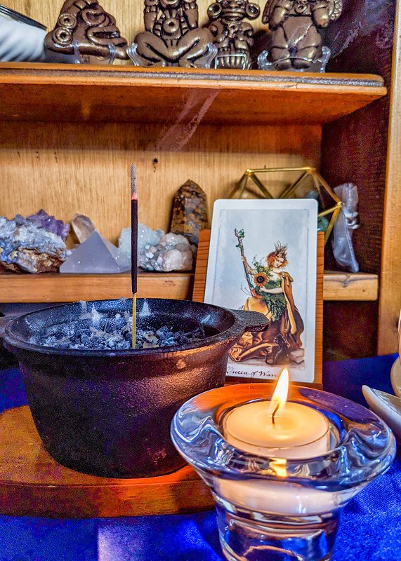 Altar with candle, incense, crystals, and tarot card.