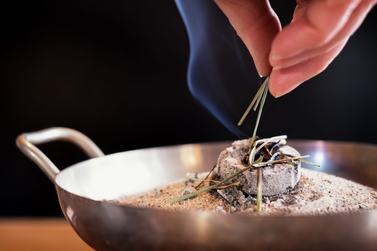 Burning herbs on charcoal in a brass container.