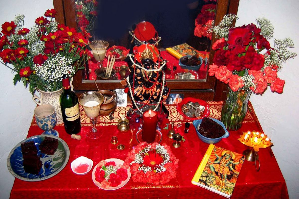 Kali altar with statue, flowers, and other ritual items.