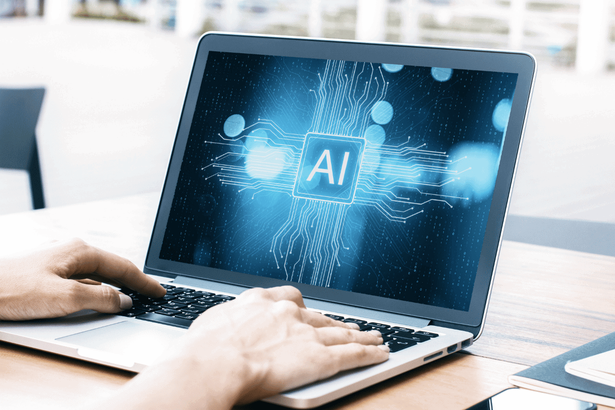 Close-up and side view of hands using laptop with AI circuit concept on screen.