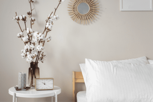 Bedside table with flowers, a candle, and clock.