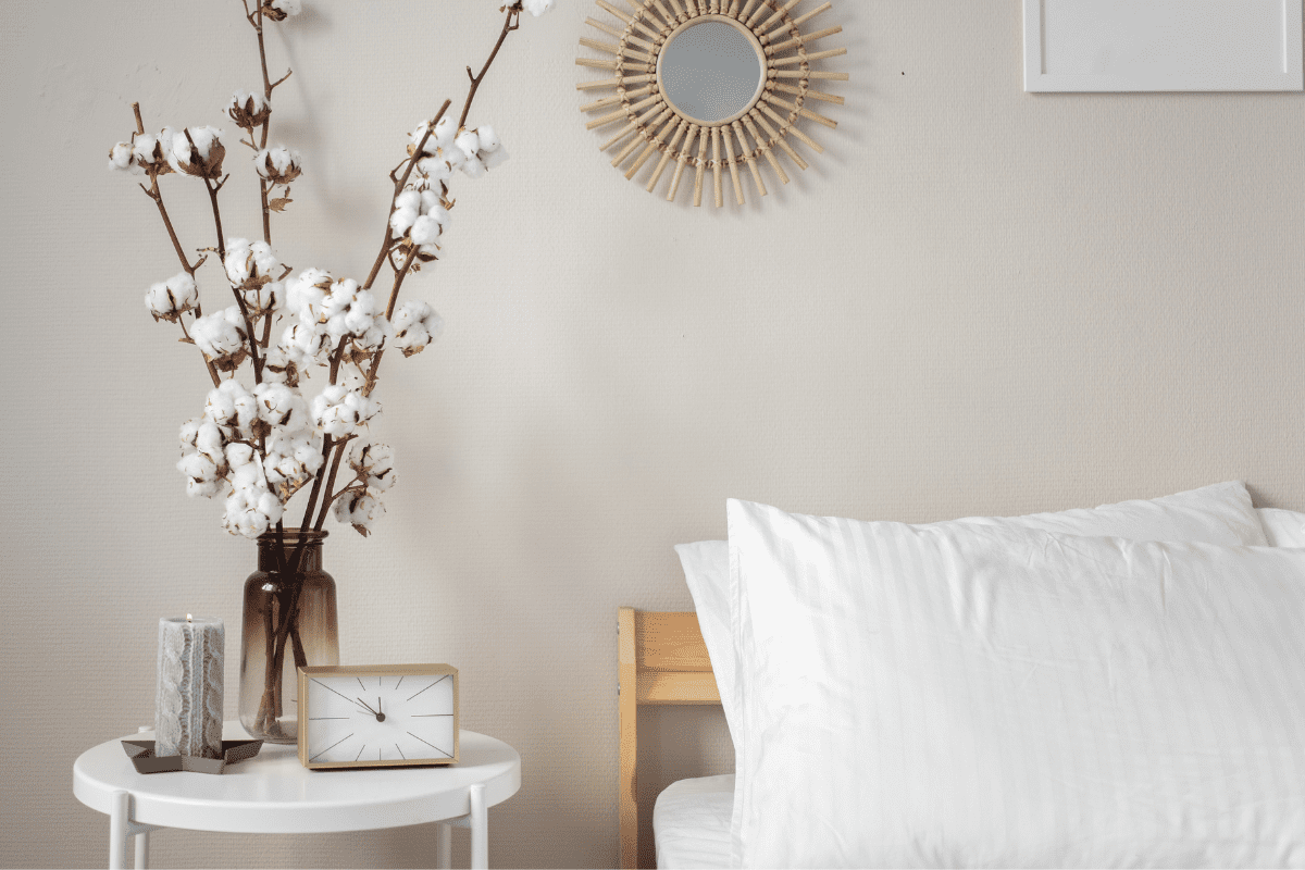 Bedside table with flowers, a candle, and clock.