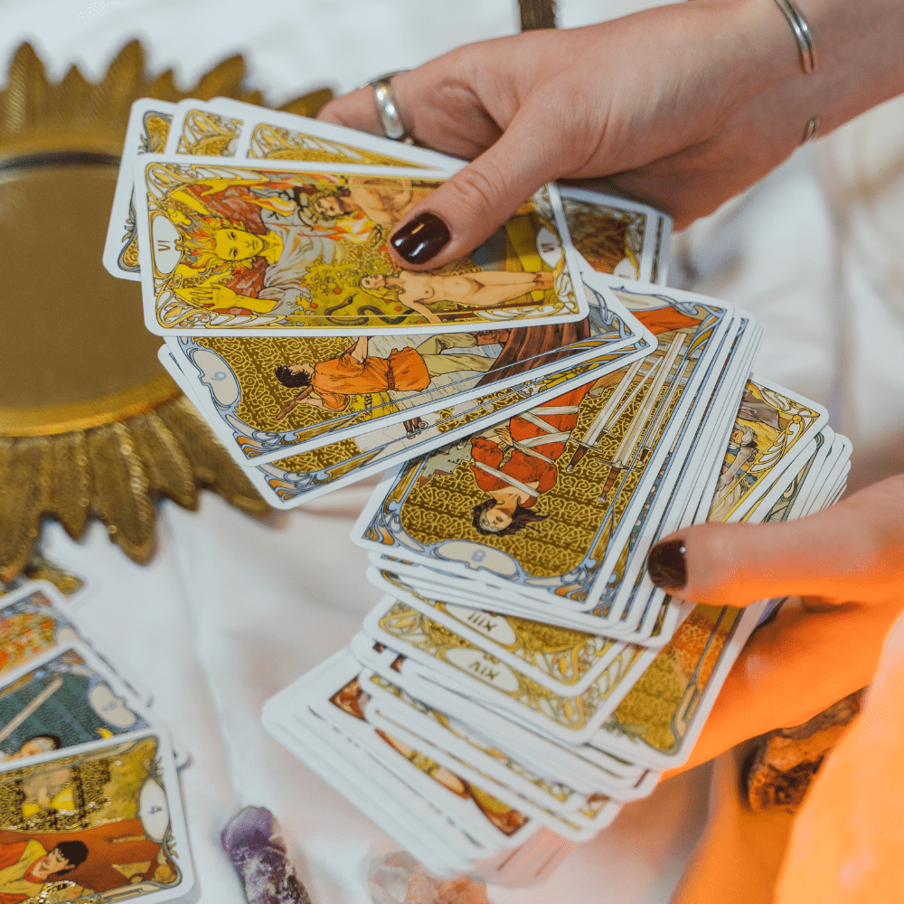 Hands holding fanned out tarot cards.