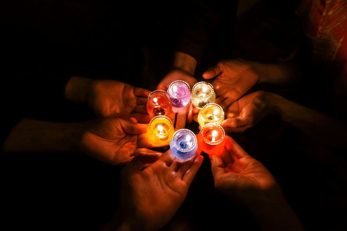 Silhouette of people holding colourful candles.
