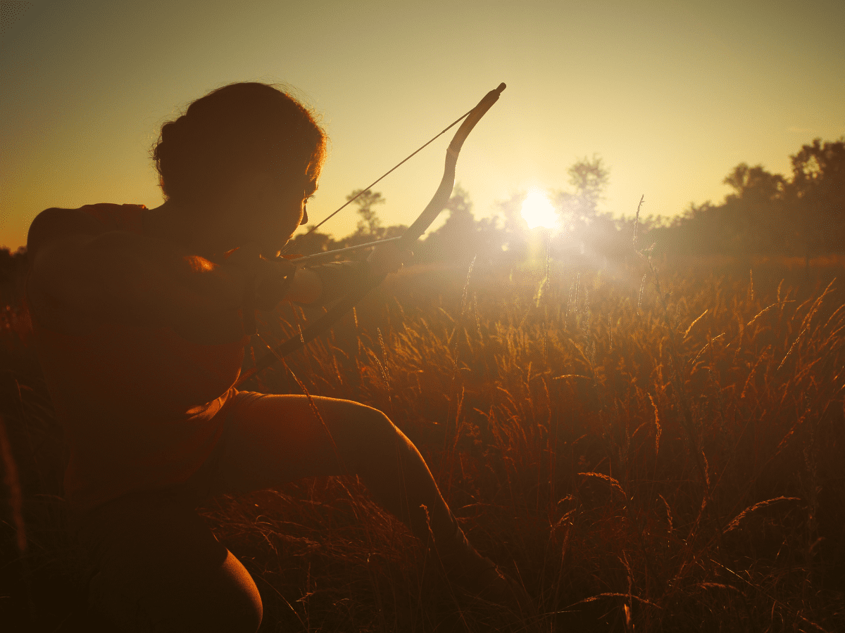 Female archer in the field at sunset