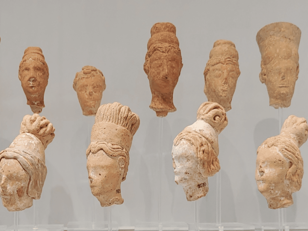 Clay heads of female figurines with elaborate hairstyles.