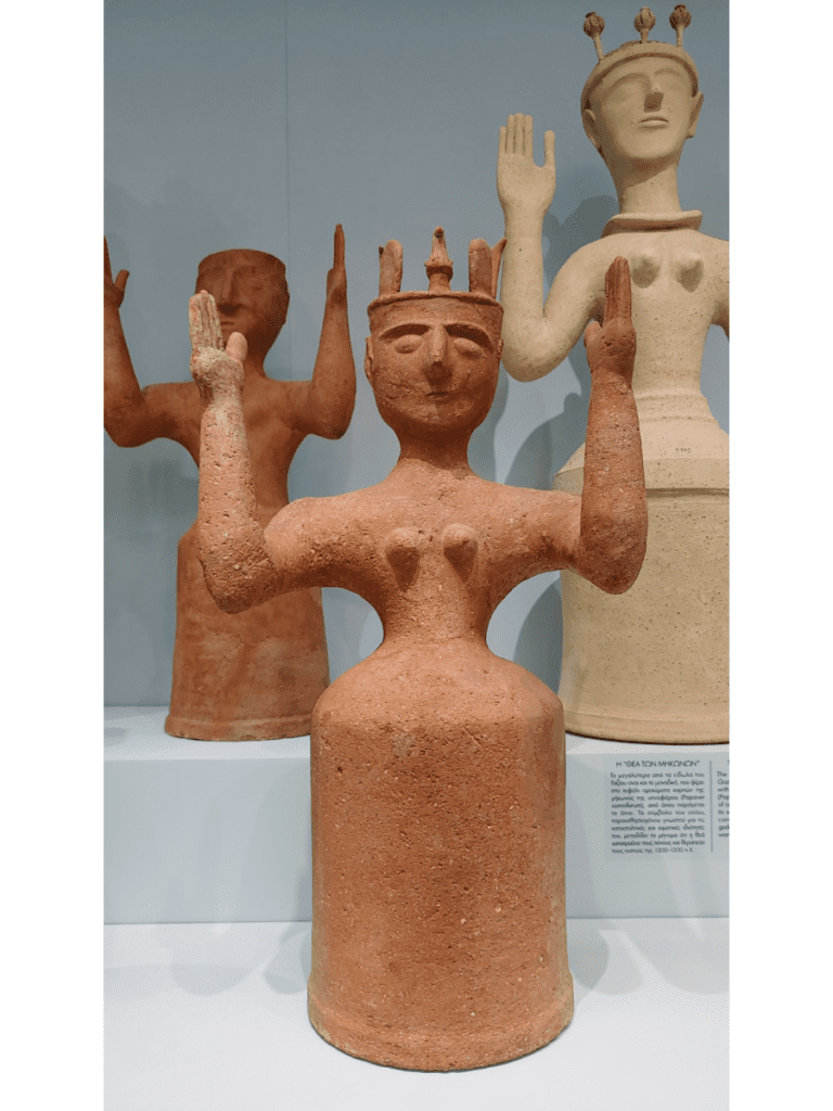 Three clay figures of goddesses with upraised arms.