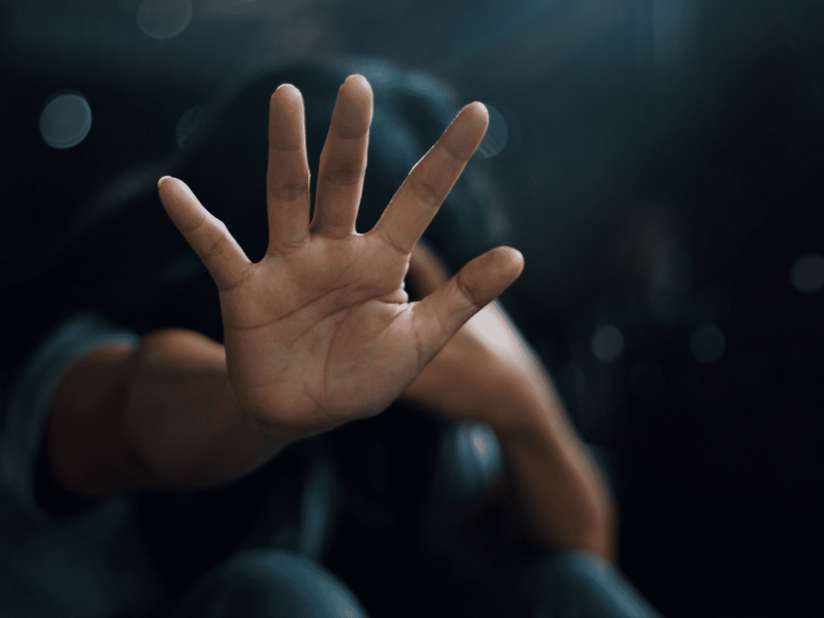 A woman sitting alone on the floor showing her palm pushing away a psychic attack.