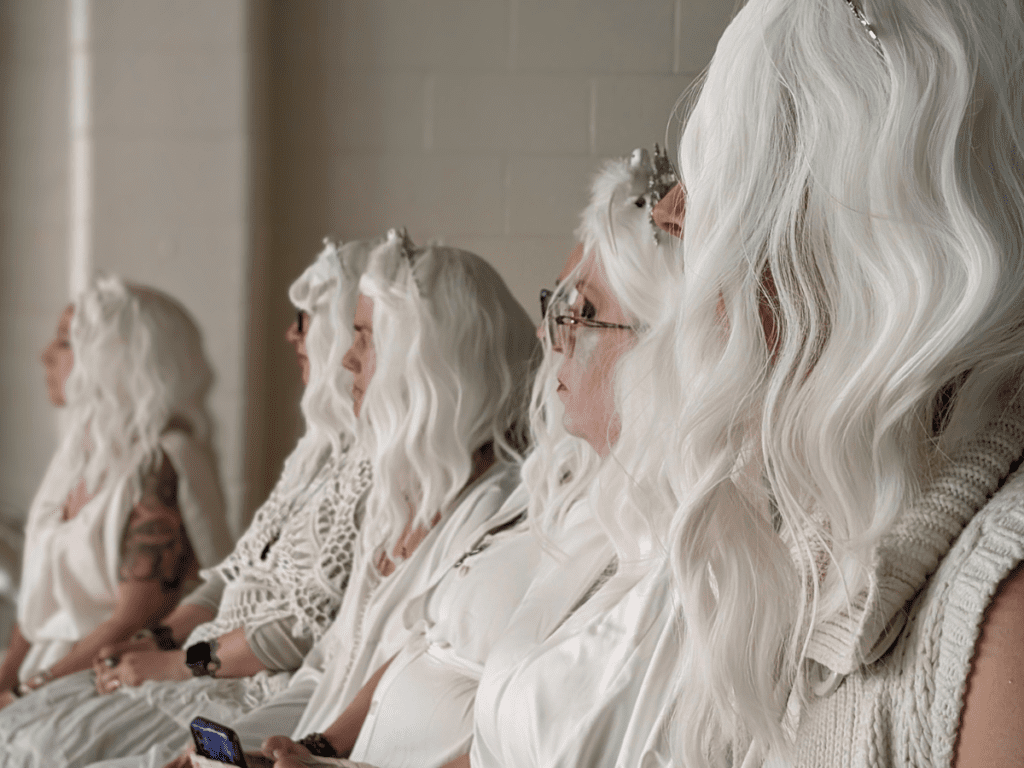 Women wearing white dresses and white wigs.
