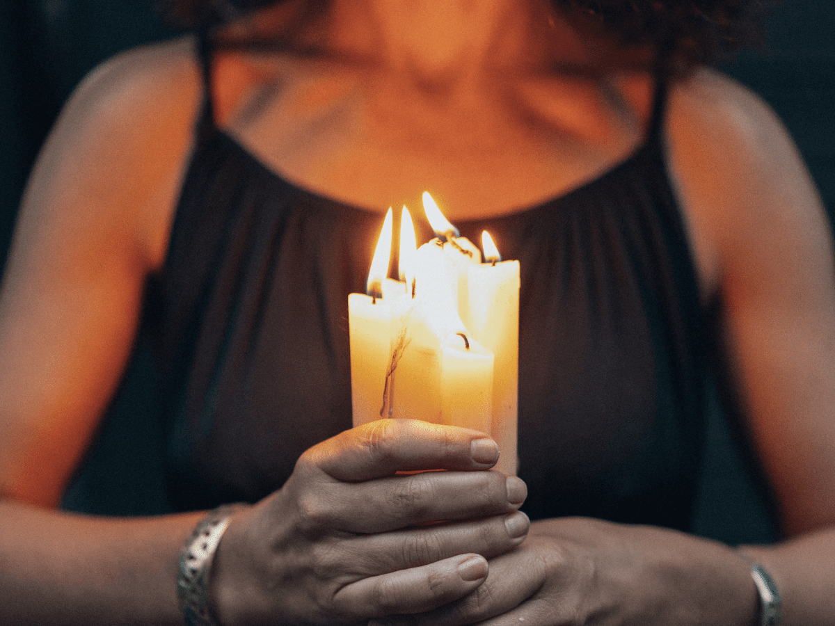 Woman holding a bunch of lit candles.