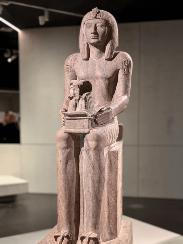 A statue of Sety II: seated on a throne, holding on his knees a shrine surmounted by a ram's head, emblem of the god Amun-Ra.