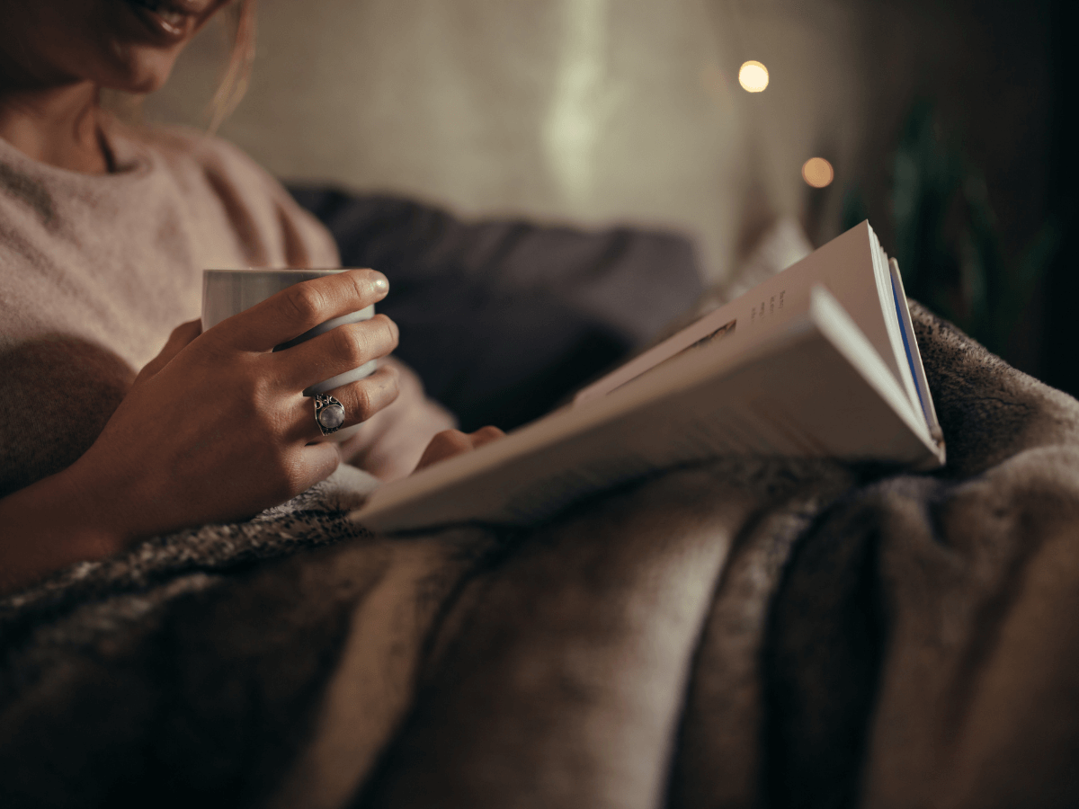 Woman holding a cup of coffee and reading a book