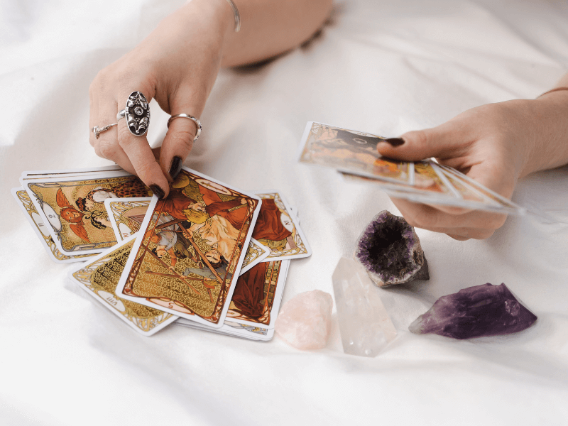 Hands holding and placing tarot cards down.