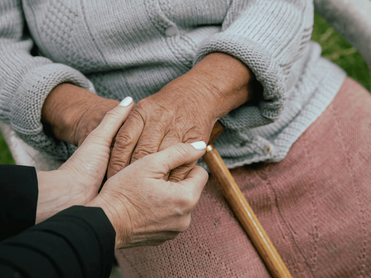 End-of-life doula holding the hands of an elderly woman.