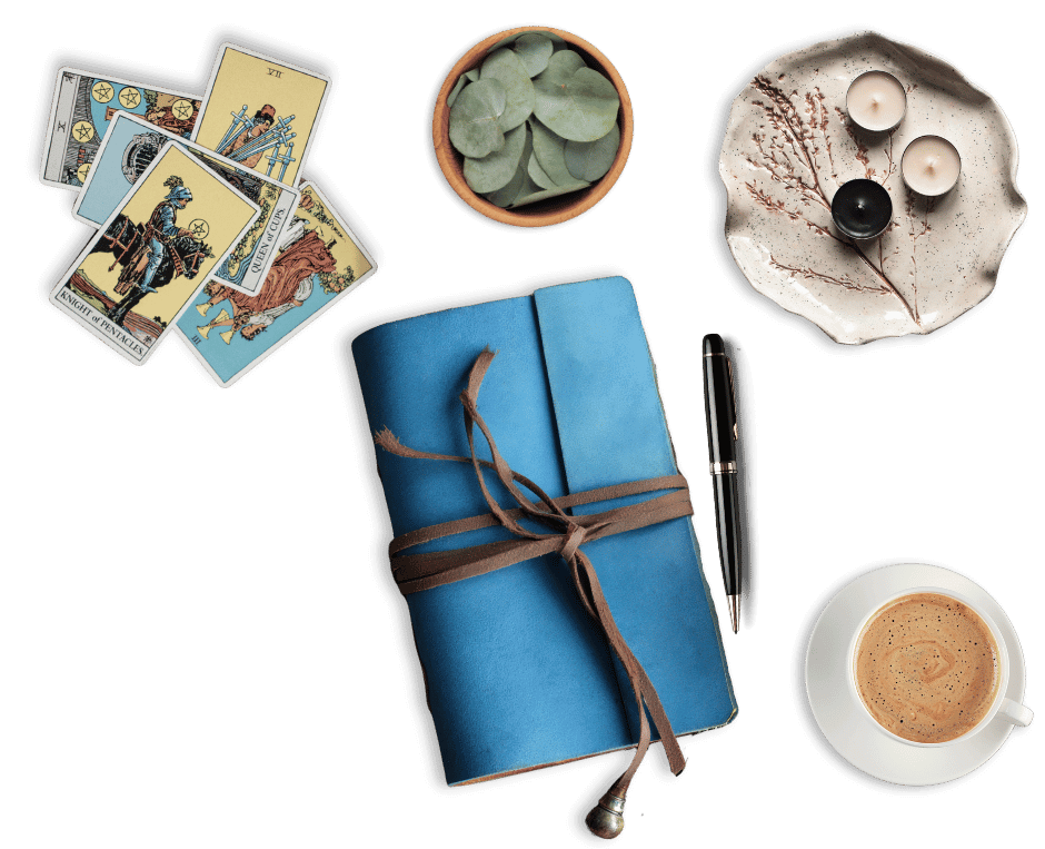 A blue journal, tarot cards, candles, and a cup of coffee.