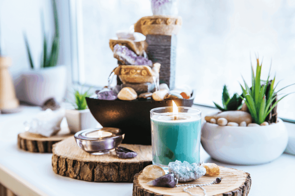 Candles, crystals and other items sit on a table in front of a window.