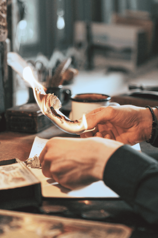 Hands holding a piece of paper lit on fire in witchcraft and spiritual development.