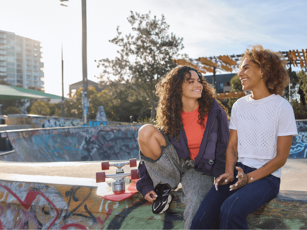 Two young women skateboarders talking.