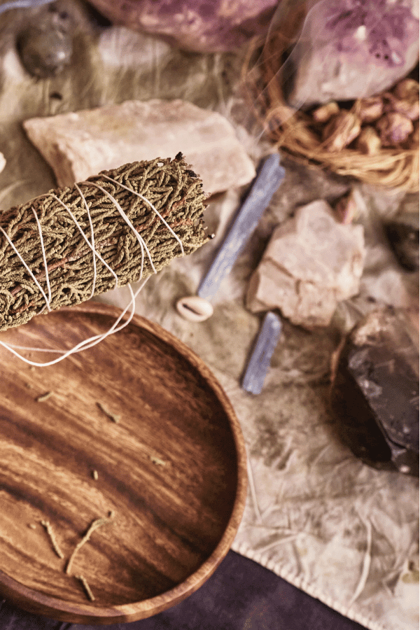 A pine bundle for smoking, crystals, cowrie shells, and flowers.