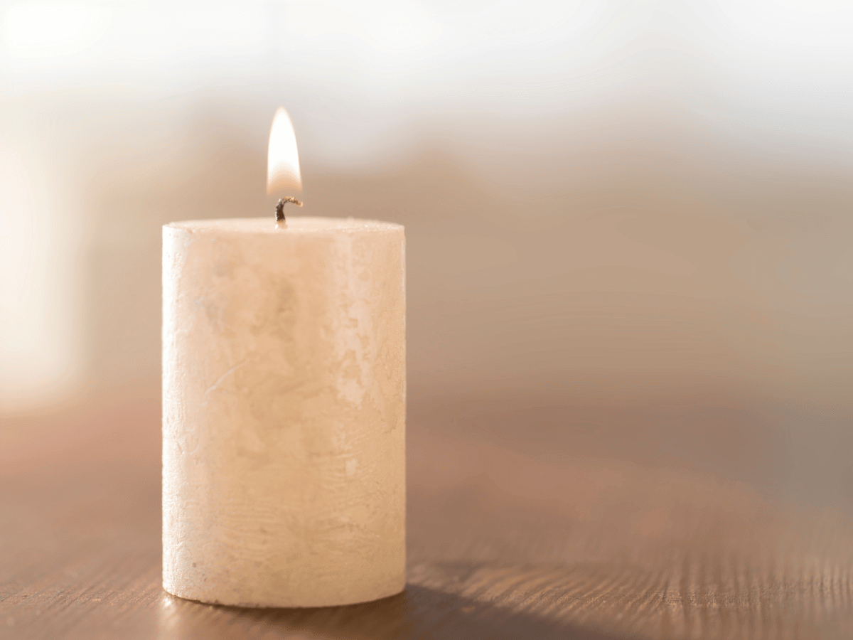 A single pillar candle on a table.