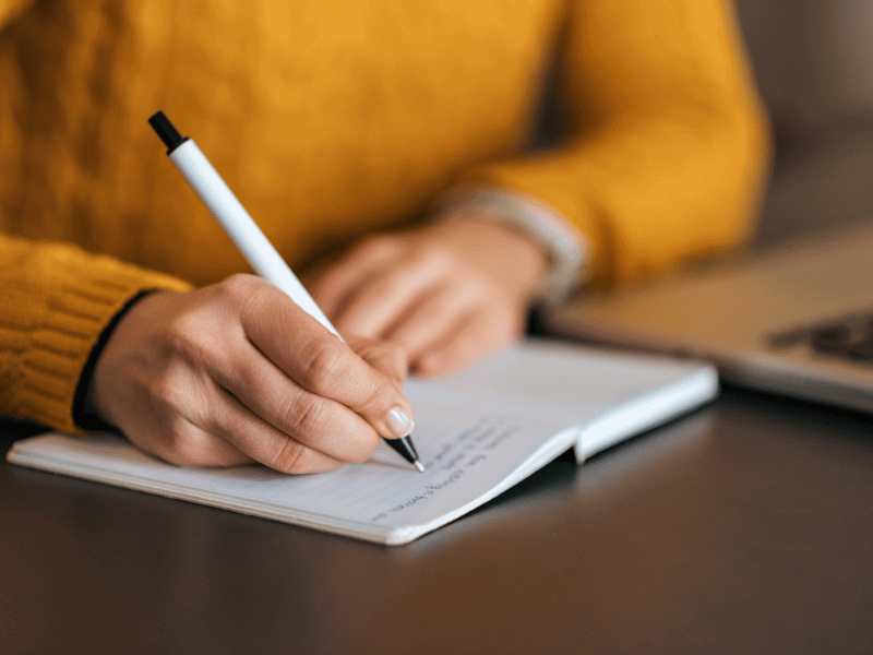 Hands writing in a notebook.