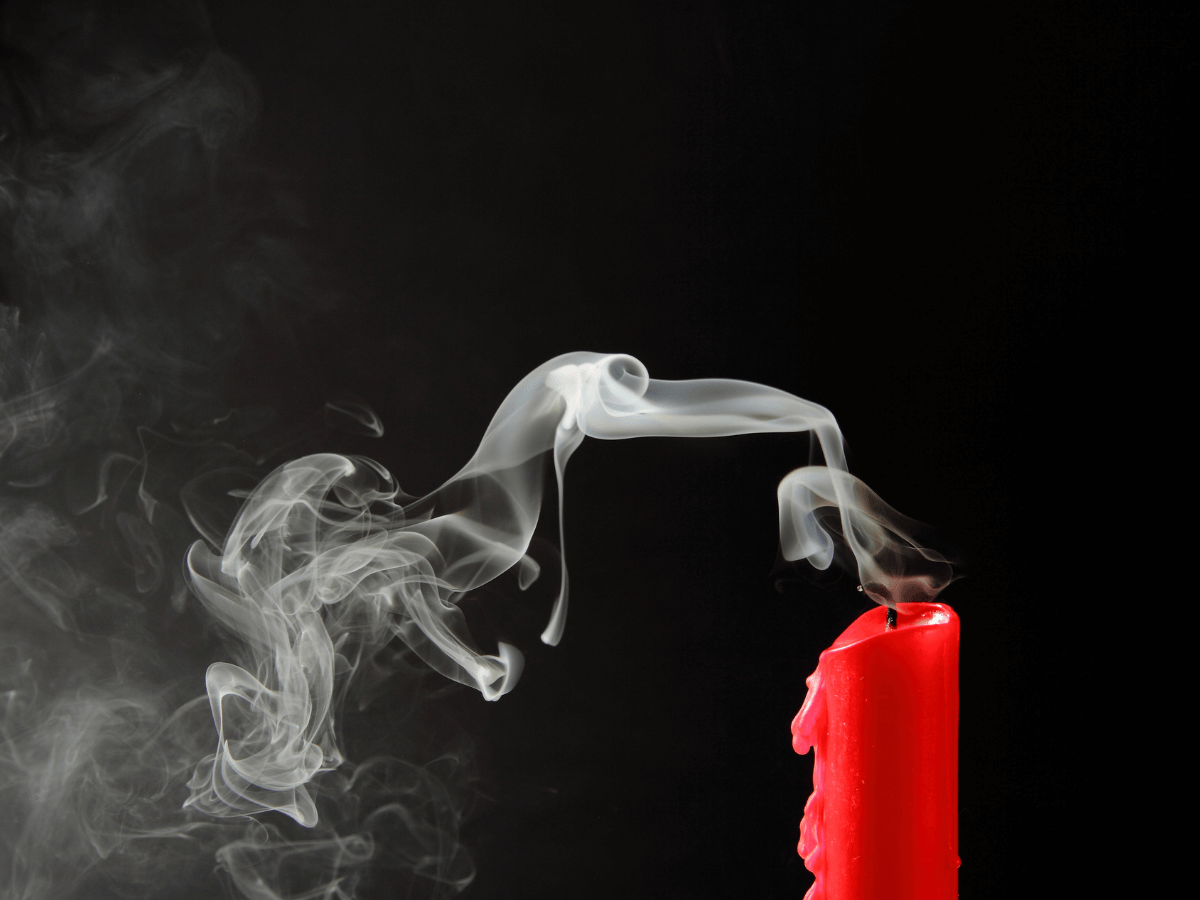 Red candle on black background after it has been extinguides.