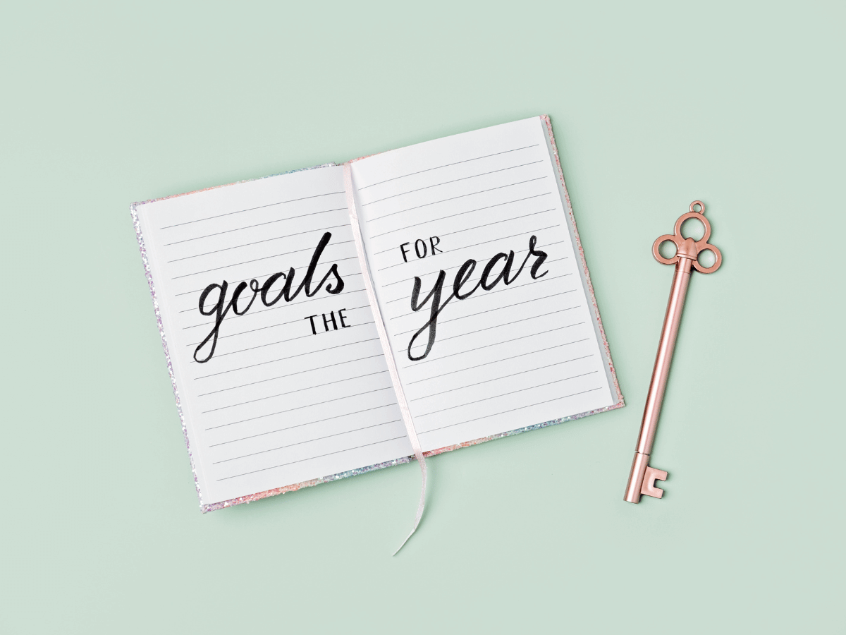 An open journal with the words, "Goals for the year." A key lies next to the journal.