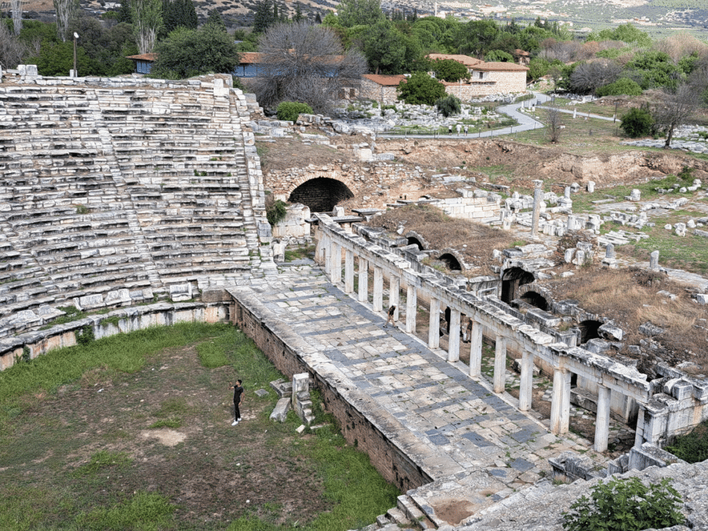 The ruined remains of a Roman theatre plus columns and other ruins in the background.