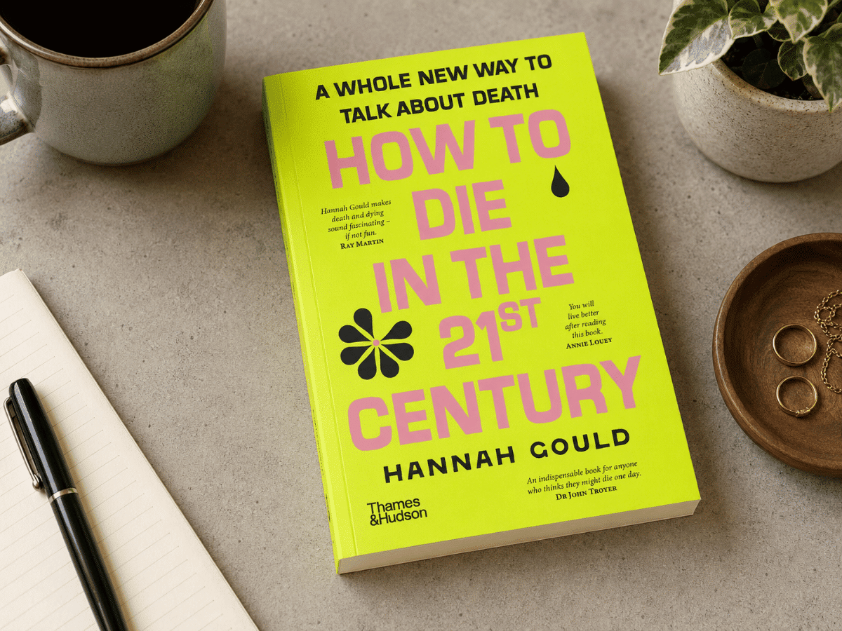 How to Die in the 21st Century book by a notebook and cup of coffee.