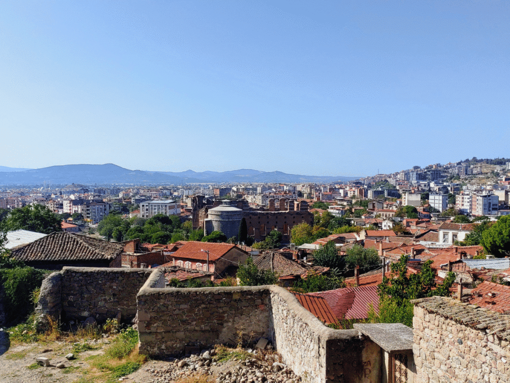 View across Bergama towards the Red Hall, its red-brick ruins and one of its rotundas visible among the surrounding buildings.