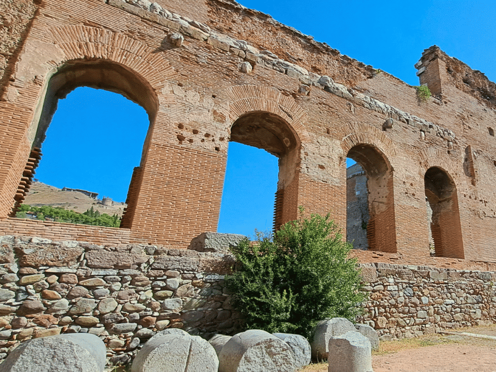 Surviving red-brick wall of the Red Hall with a row of tall arched openings.