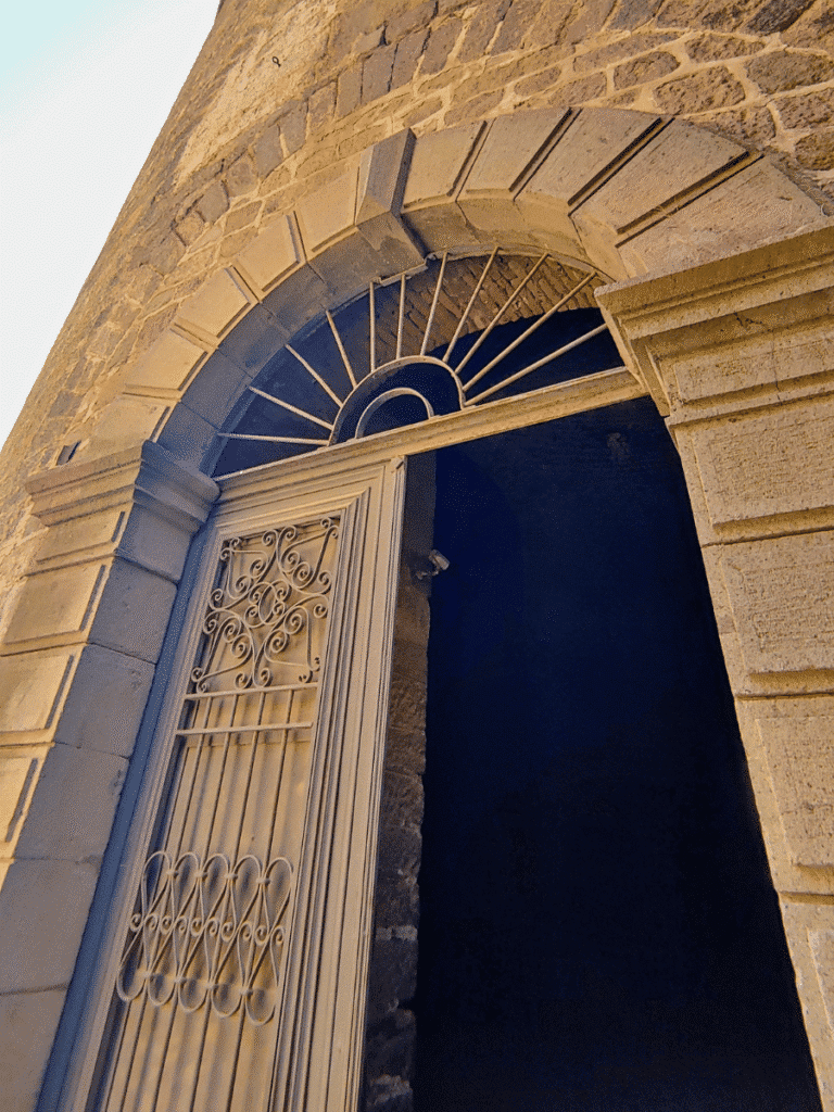 Arched stone entrance with a decorative metal gate leading into a rotunda at the Red Hall.