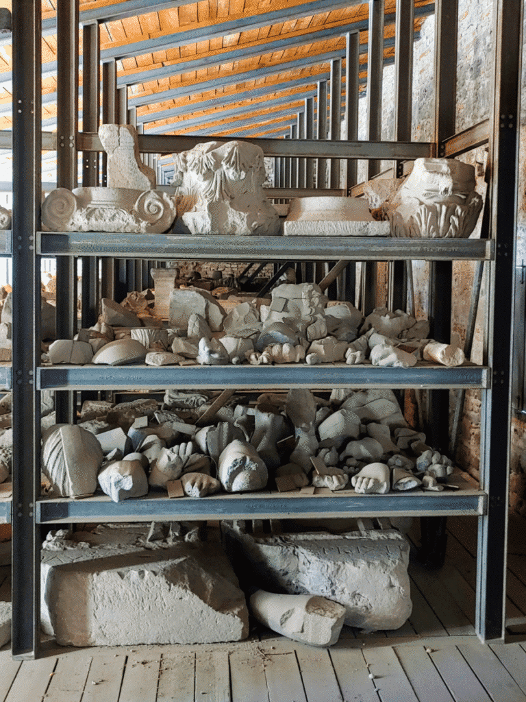 Shelves filled with marble architectural and sculptural fragments stored inside a Red Hall rotunda.
