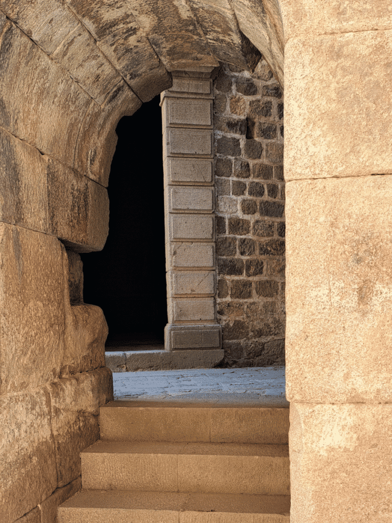 Stone steps and arched doorways passing through the thick masonry of a Red Hall rotunda.