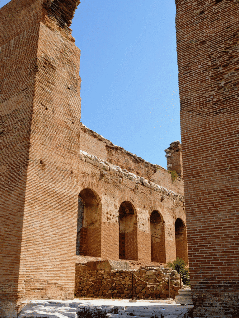 View between two towering red-brick walls towards a row of arched openings inside the Red Hall.