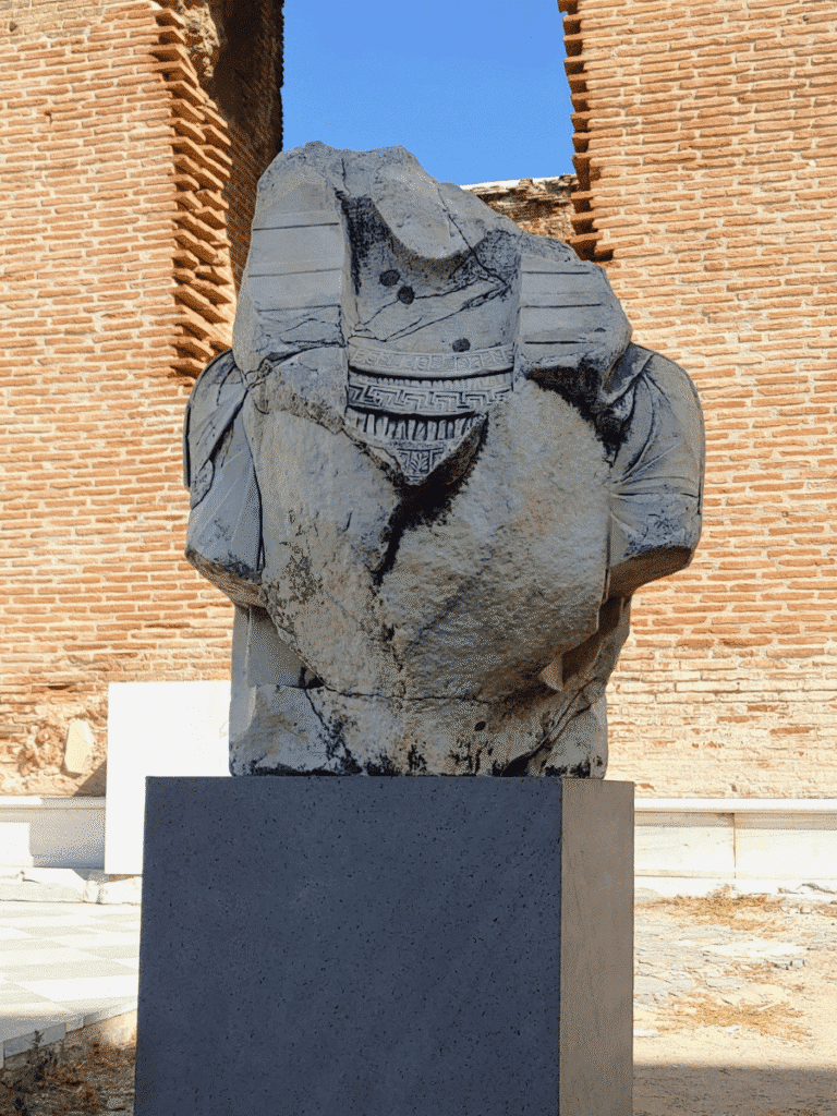 Fragmentary torso of an Egyptianising figure wearing a nemes headcloth and intricately patterned collar.