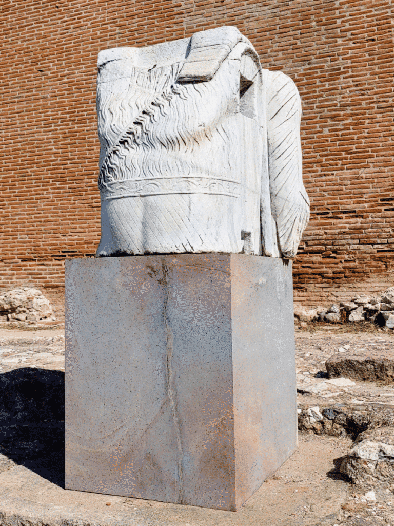 Rear view of a large sculptural fragment showing deeply carved hair or drapery and a striped nemes headcloth.