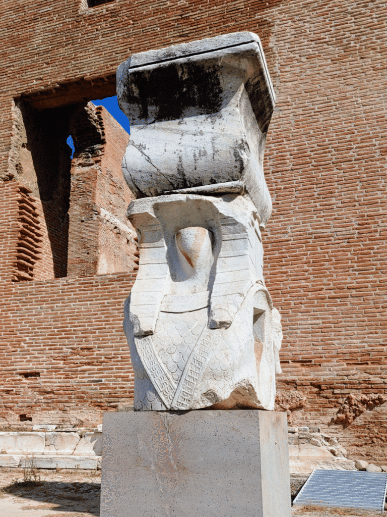 Fragmentary Egyptianising figure wearing a nemes headcloth and patterned garment, supporting a large architectural element.